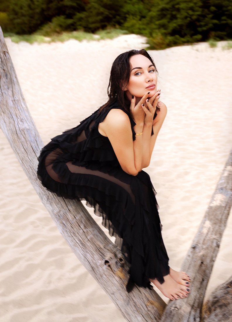 Portrait of Indre in a black ruffled dress on the beach